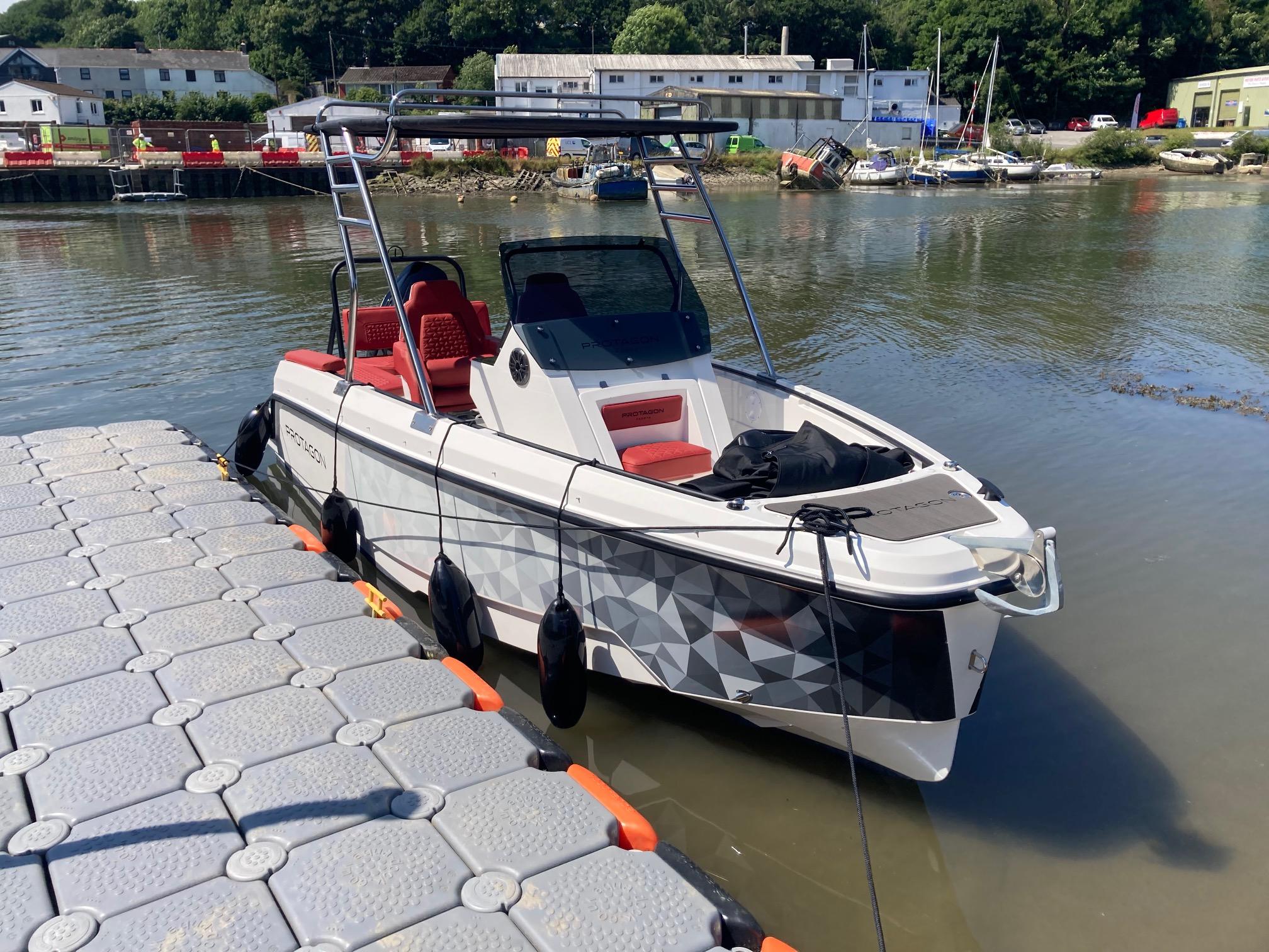 Protagon 20 Protagon 20 boat docked by the river, featuring modern design and red seating, 2025 model.