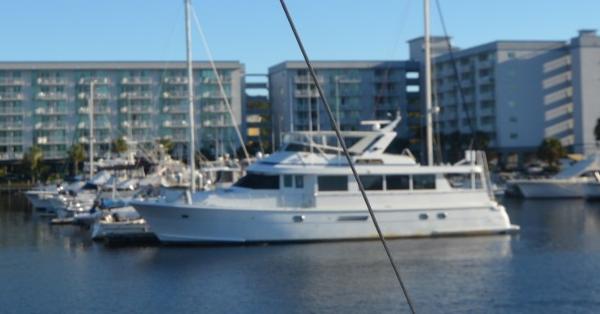Hatteras 74 Sport Deck 1998 Hatteras 74 Sport Deck yacht docked in marina, with modern buildings in background.