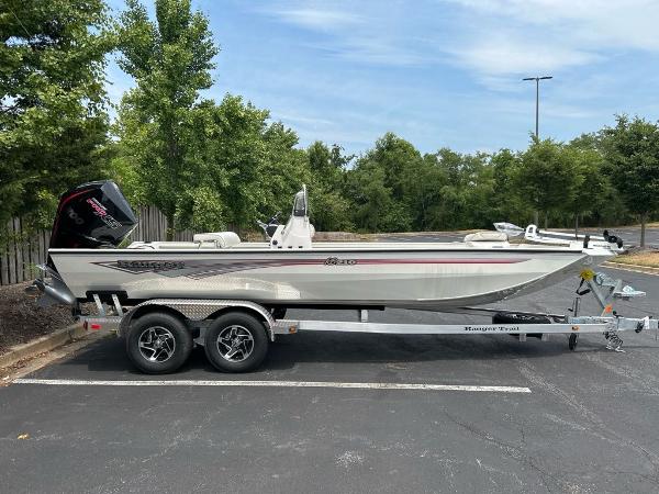 Ranger RB210 2024 Ranger RB210 boat on trailer in parking lot, surrounded by trees.