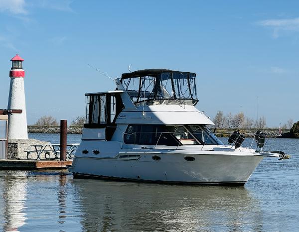 Carver 326 Aft Cabin Motor Yacht 1999 Carver 326 Aft Cabin yacht docked near a lighthouse on a sunny day.