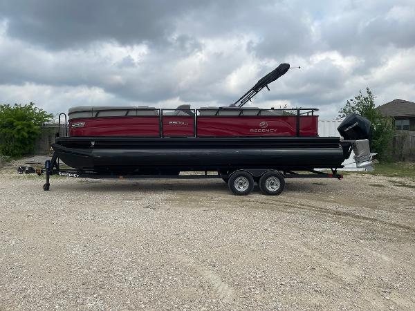 Regency 250 DL3 2022 Regency 250 DL3 pontoon boat on trailer, parked outdoors under cloudy sky.