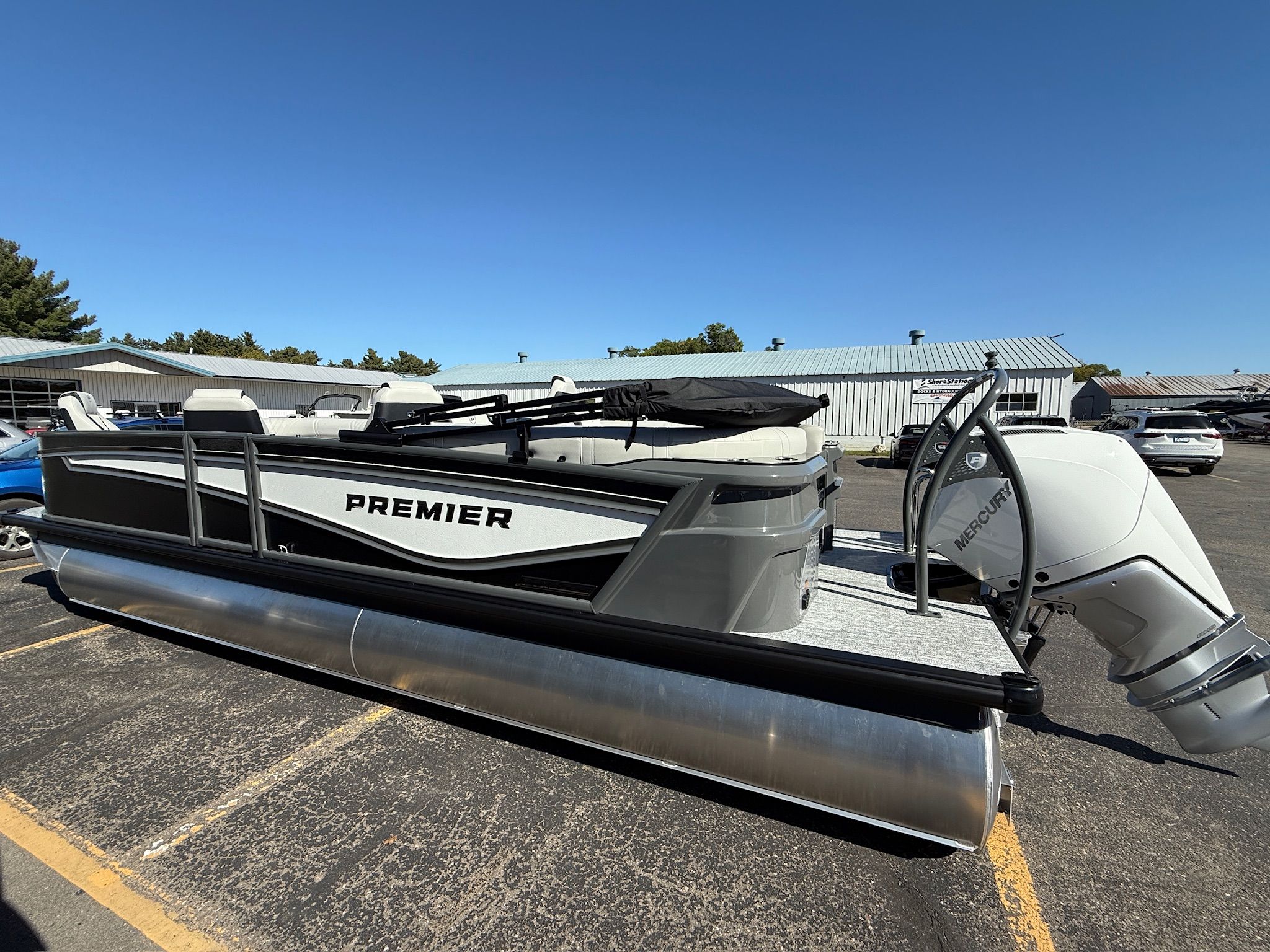 Premier 250INTRIGUE 2026 Premier 250INTRIGUE pontoon boat with Mercury engine, parked outdoors under clear blue sky.