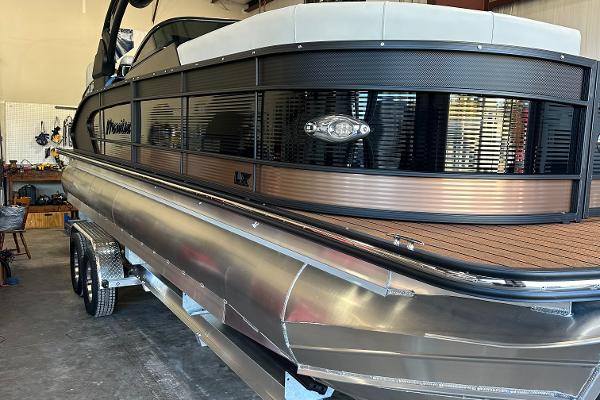 Manitou 25LX SRW 2024 Manitou 25LX SRW pontoon boat in a garage.