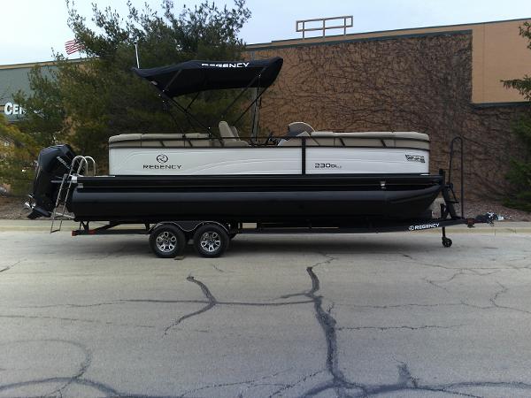 Regency 230 DL3 2024 Regency 230 DL3 pontoon boat on a trailer, parked outdoors.