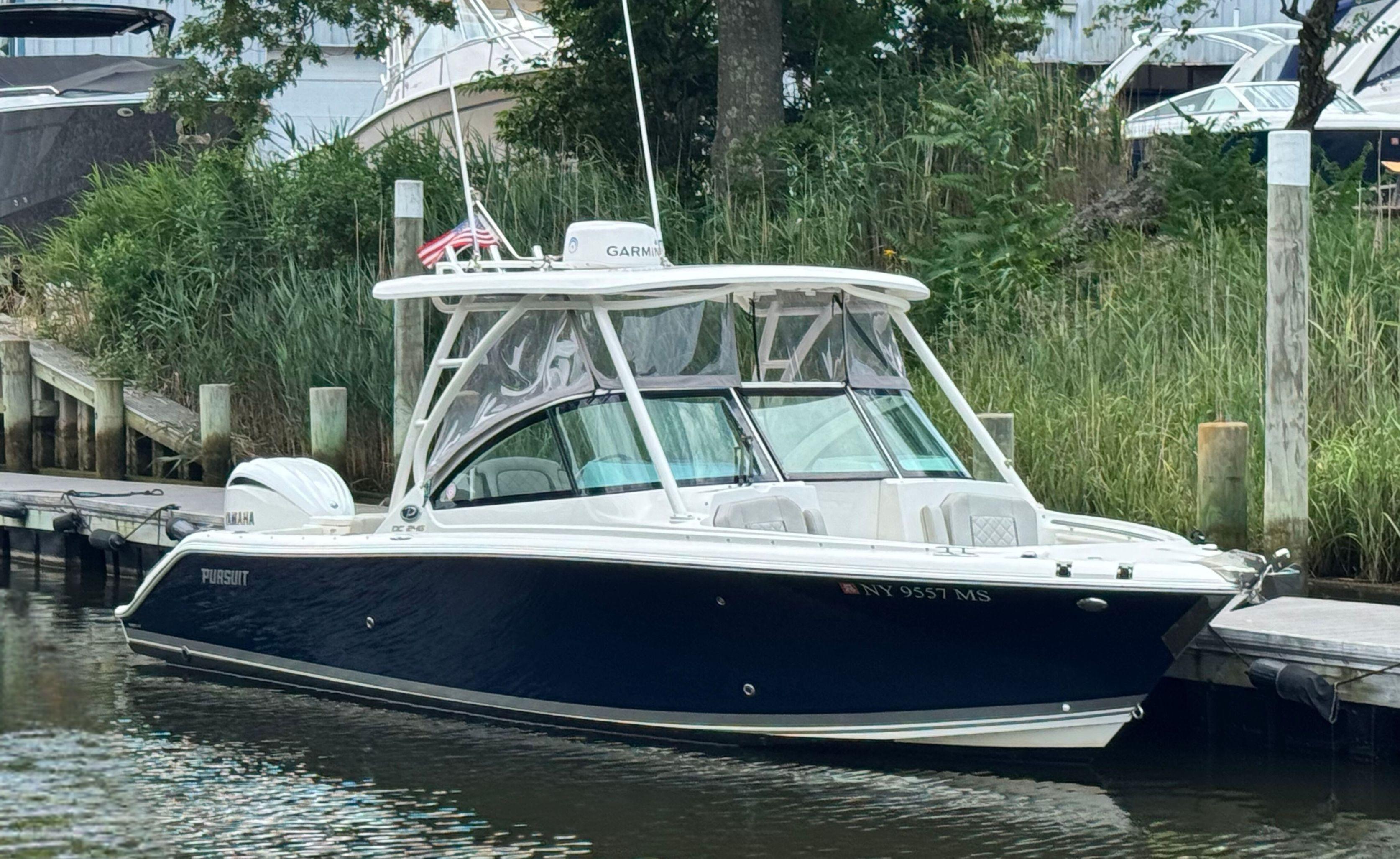 Pursuit DC 246 Dual Console 2023 Pursuit DC 246 Dual Console boat docked by lush greenery.