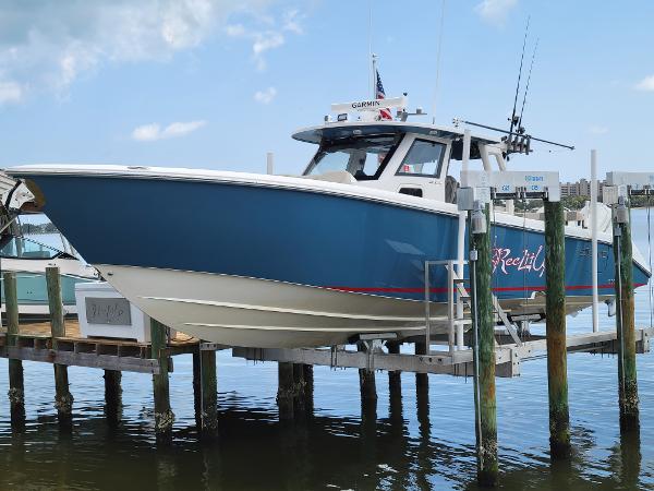 Solace 41 CS 2023 Solace 41 CS boat docked, blue hull, fishing rods, clear sky.