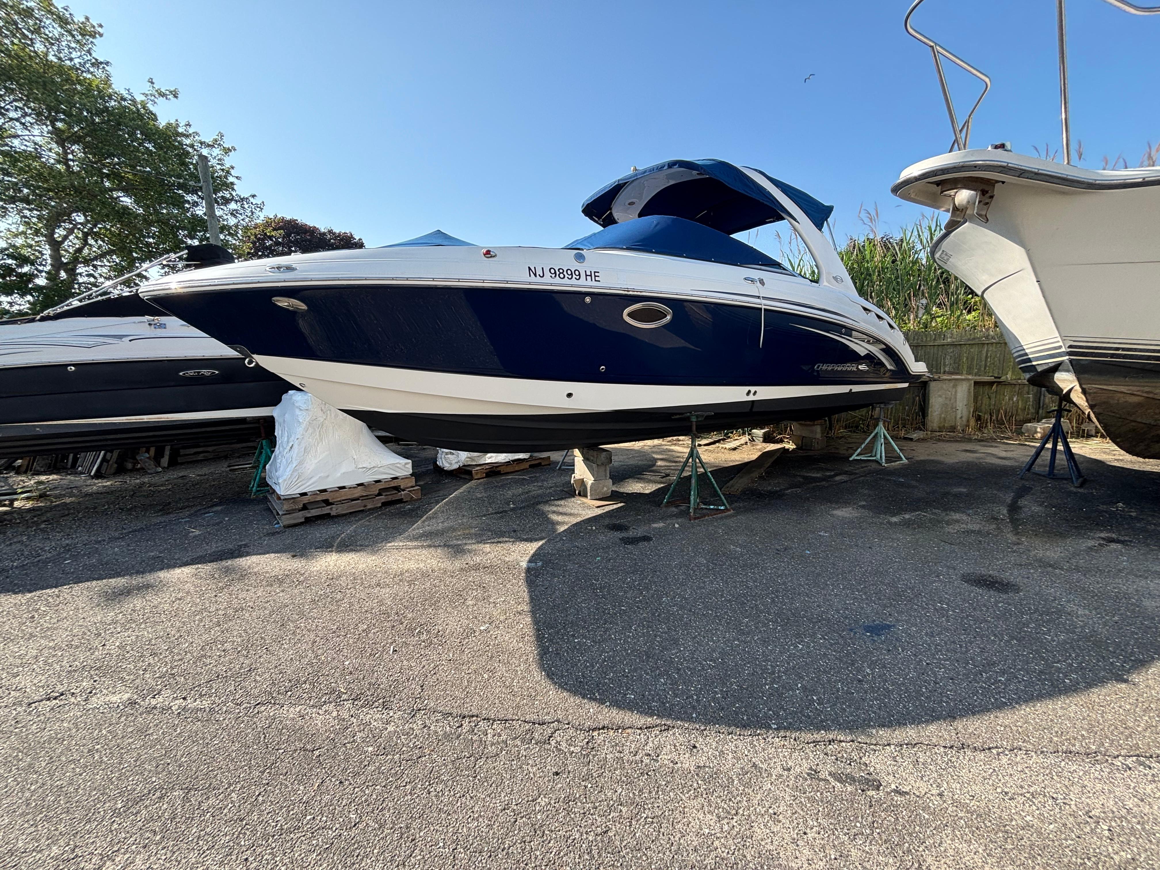 Chaparral 287 SSX 2012 Chaparral 287 SSX boat on stands, blue and white hull, parked outdoors.