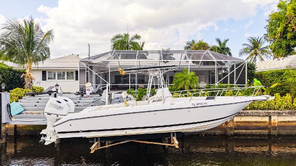 Century 2600 CC Century 2600 CC boat from 1999 docked by a waterfront home with lush greenery.