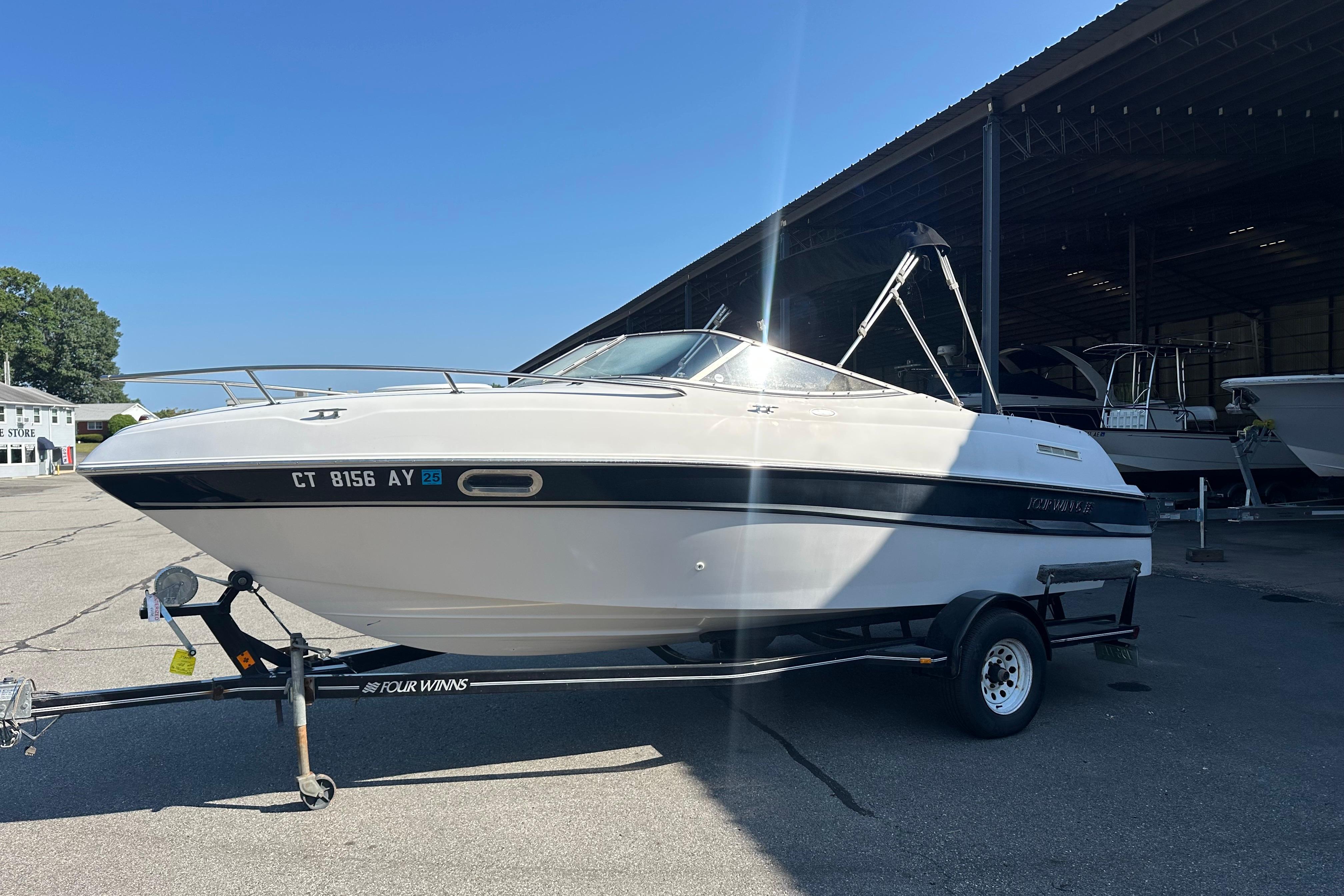 Four Winns 205 Sundowner 2002 Four Winns 205 Sundowner boat on trailer in sunny marina setting.