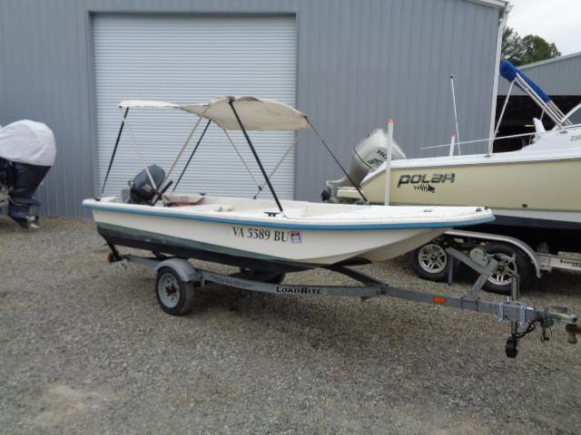 Sundance K14T Small Sundance K14T boat on trailer, parked outside a garage, with canopy and motor.