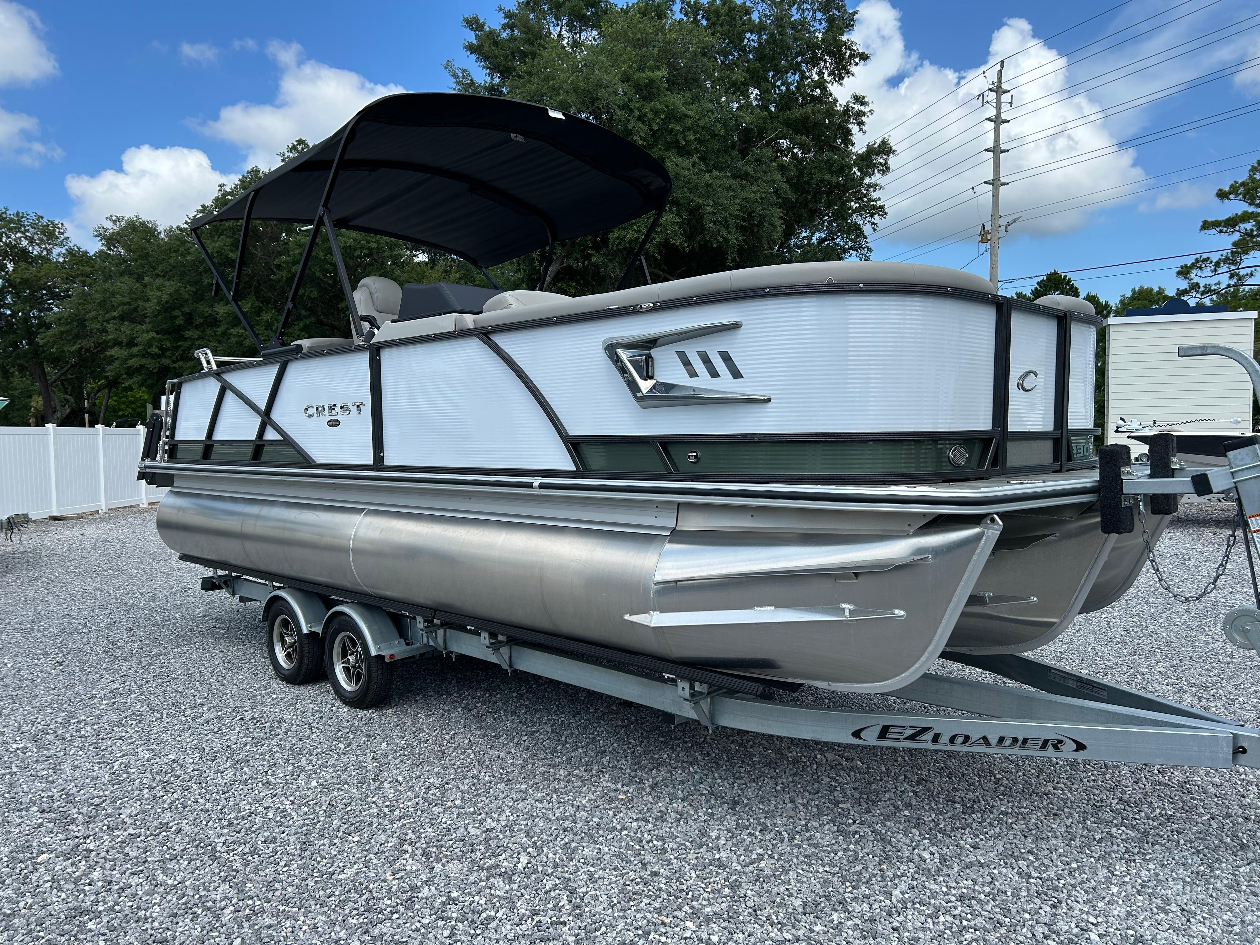 Crest Caribbean LX 230 2024 Crest Caribbean LX 230 pontoon boat on trailer, parked outdoors.