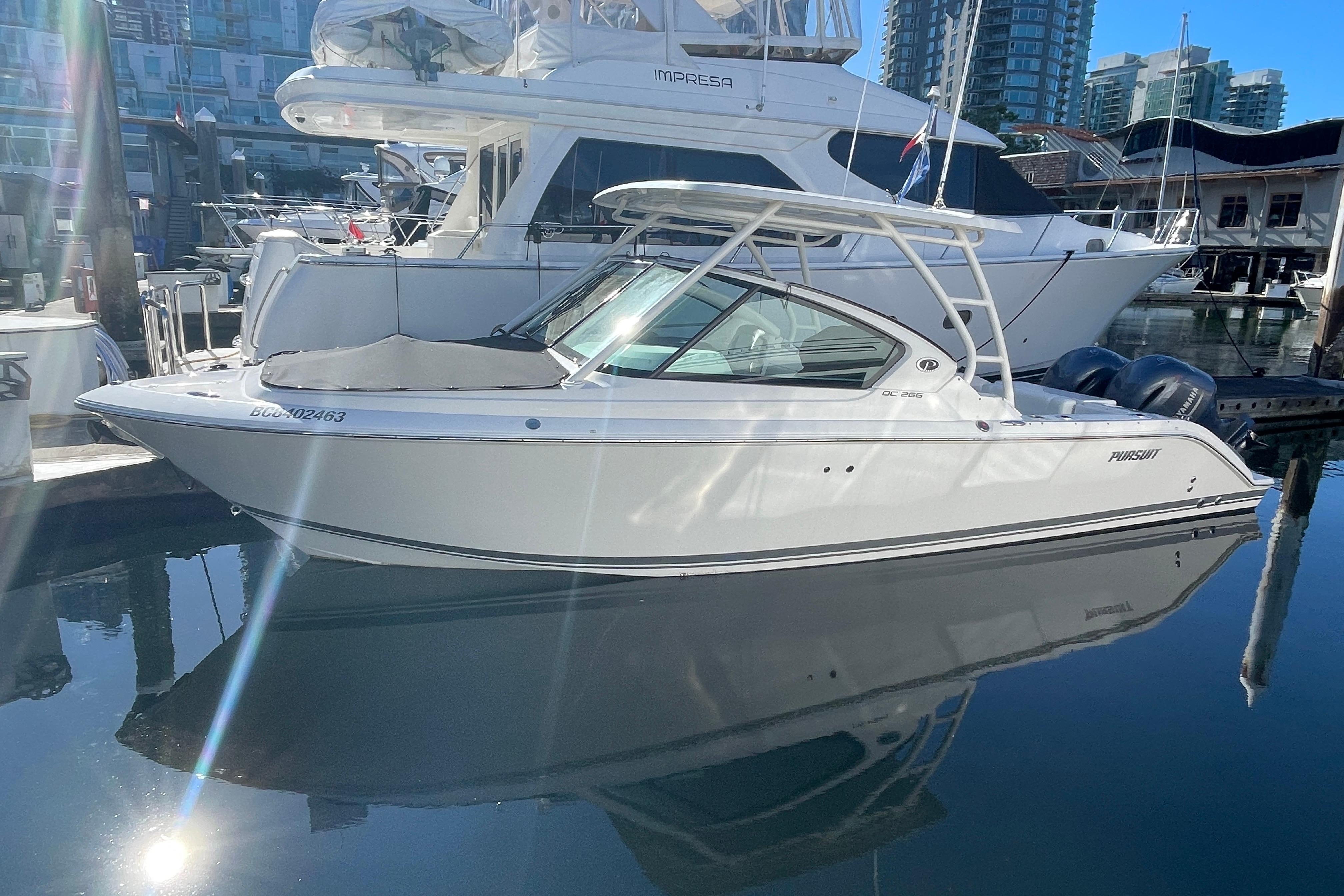 Pursuit DC 266 Dual Console 2023 Pursuit DC 266 Dual Console boat docked in marina, reflecting on water.