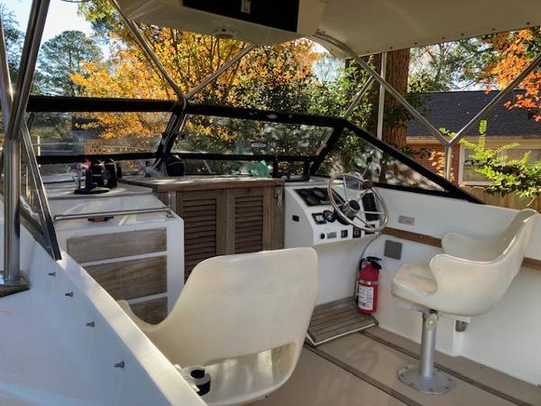 Albemarle 24 Cuddy 1986 Albemarle 24 Cuddy boat interior with steering wheel and seating, surrounded by autumn foliage.