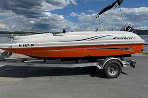 Starcraft 1915 OB Limited 2022 Starcraft Limited 1915 OB boat on trailer, orange and white design, parked by a lake.