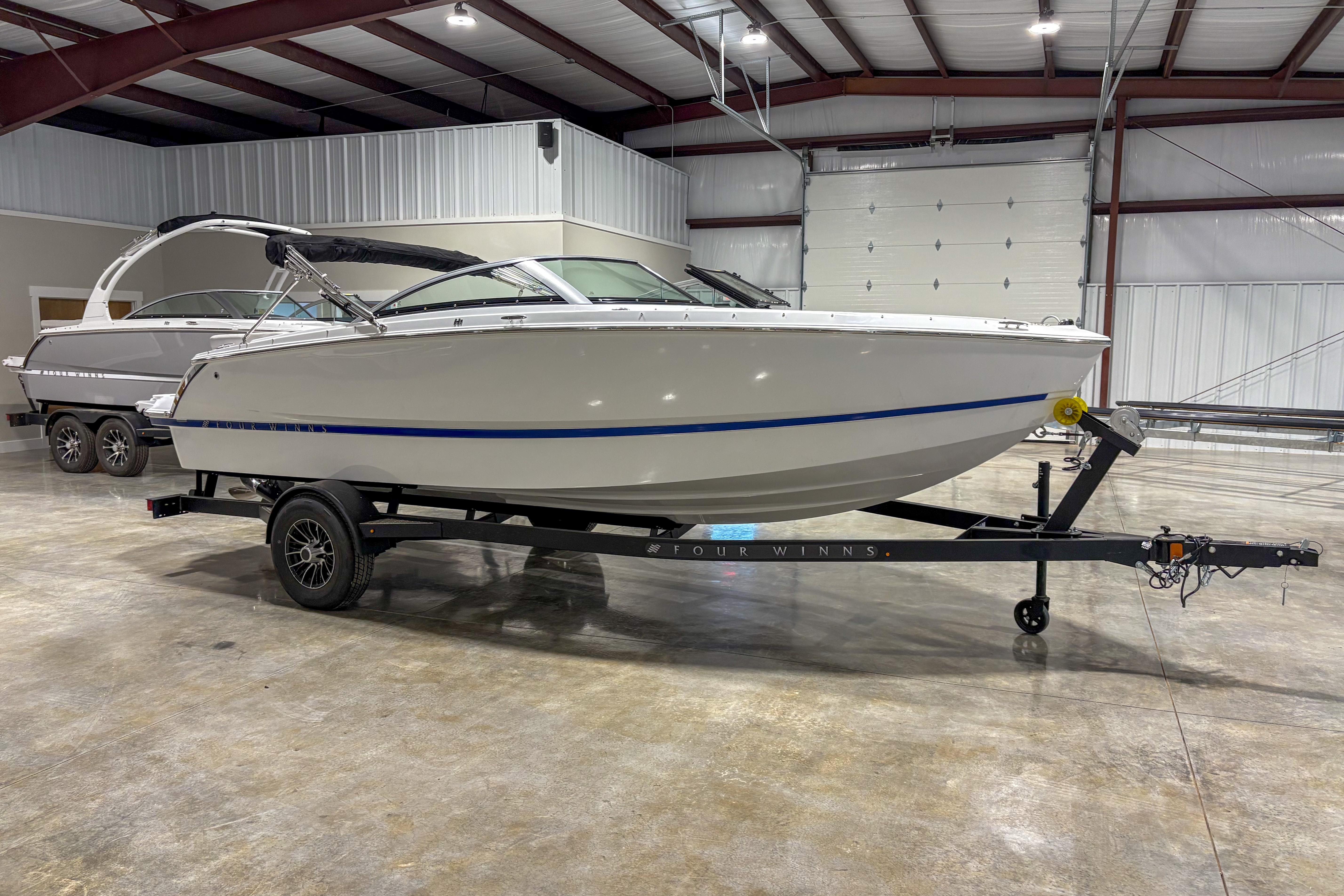 Four Winns H1 2026 Four Winns H1 boat on trailer in indoor storage facility.