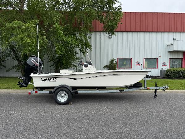 Mako Pro Skiff 15 CC 2025 Mako Pro Skiff 15 CC boat on trailer, parked outdoors near industrial building.