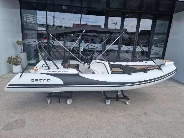 Grand G500HGLF White Decor 2025 Grand G500HGLF White Decor boat displayed on wheeled stands outside a showroom.