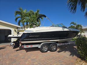 Monterey 254FS 2010 Monterey 254FS boat on trailer, parked in driveway with palm trees and clear blue sky.