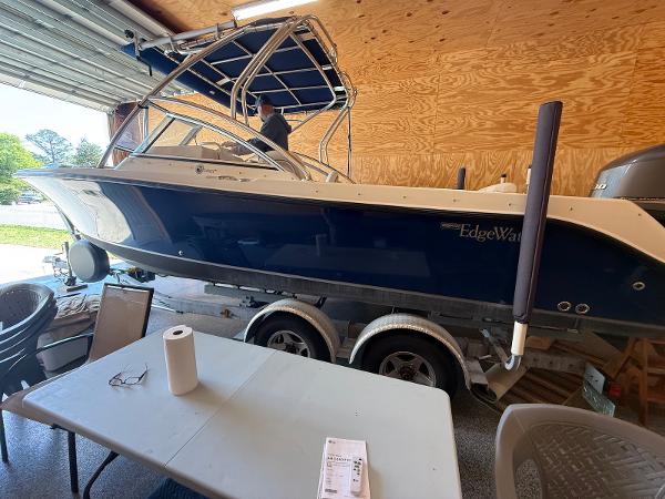 Edgewater 245 CX 2012 Edgewater 245 CX boat in garage, blue hull, on trailer, with table and chairs nearby.