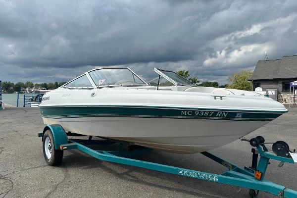 Four Winns Horizon 1997 Four Winns Horizon QX boat on trailer, parked near a dock under cloudy skies.