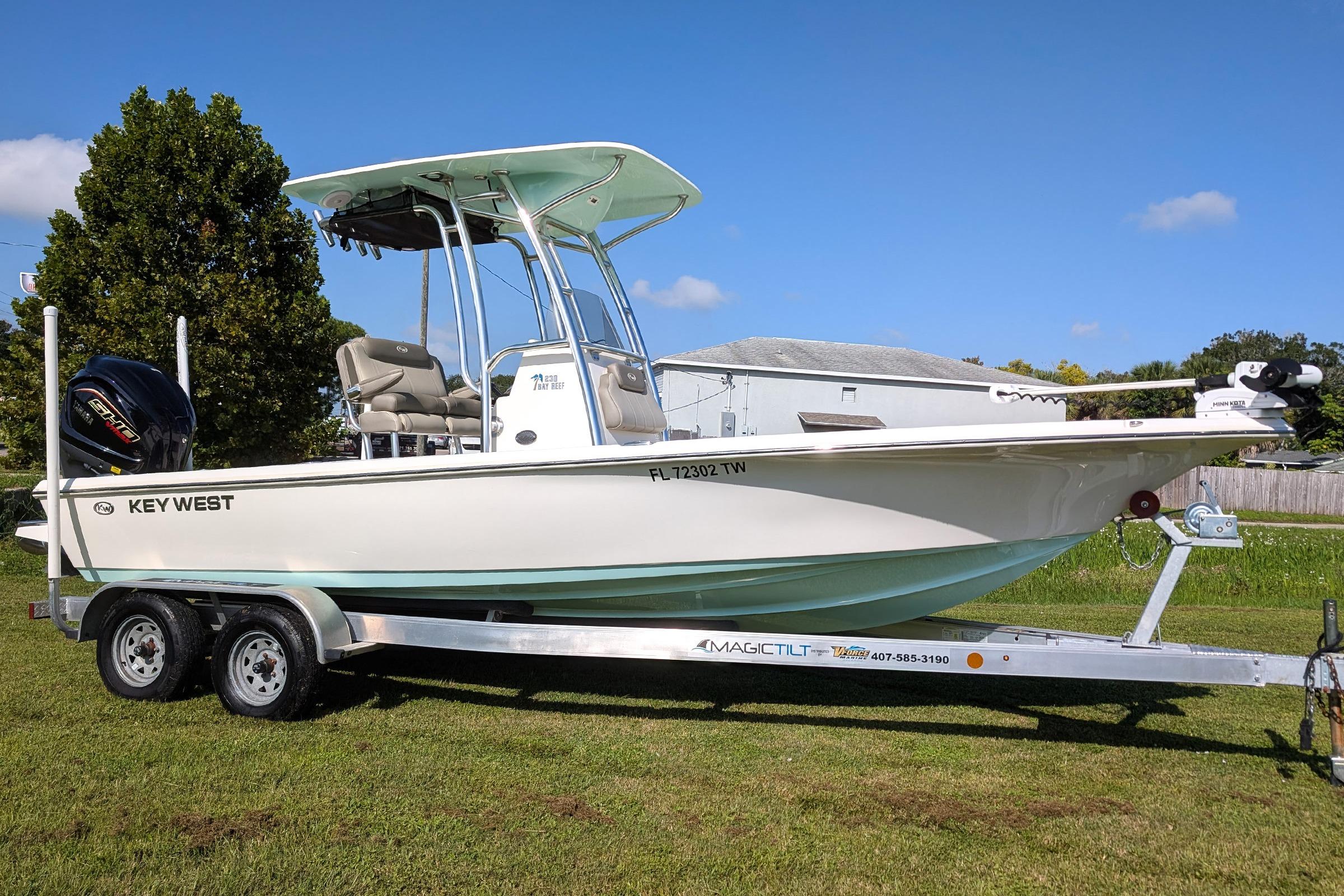 Key West 230 Bay Reef 2023 Key West 230 Bay Reef boat on trailer, parked on grass under clear blue sky.