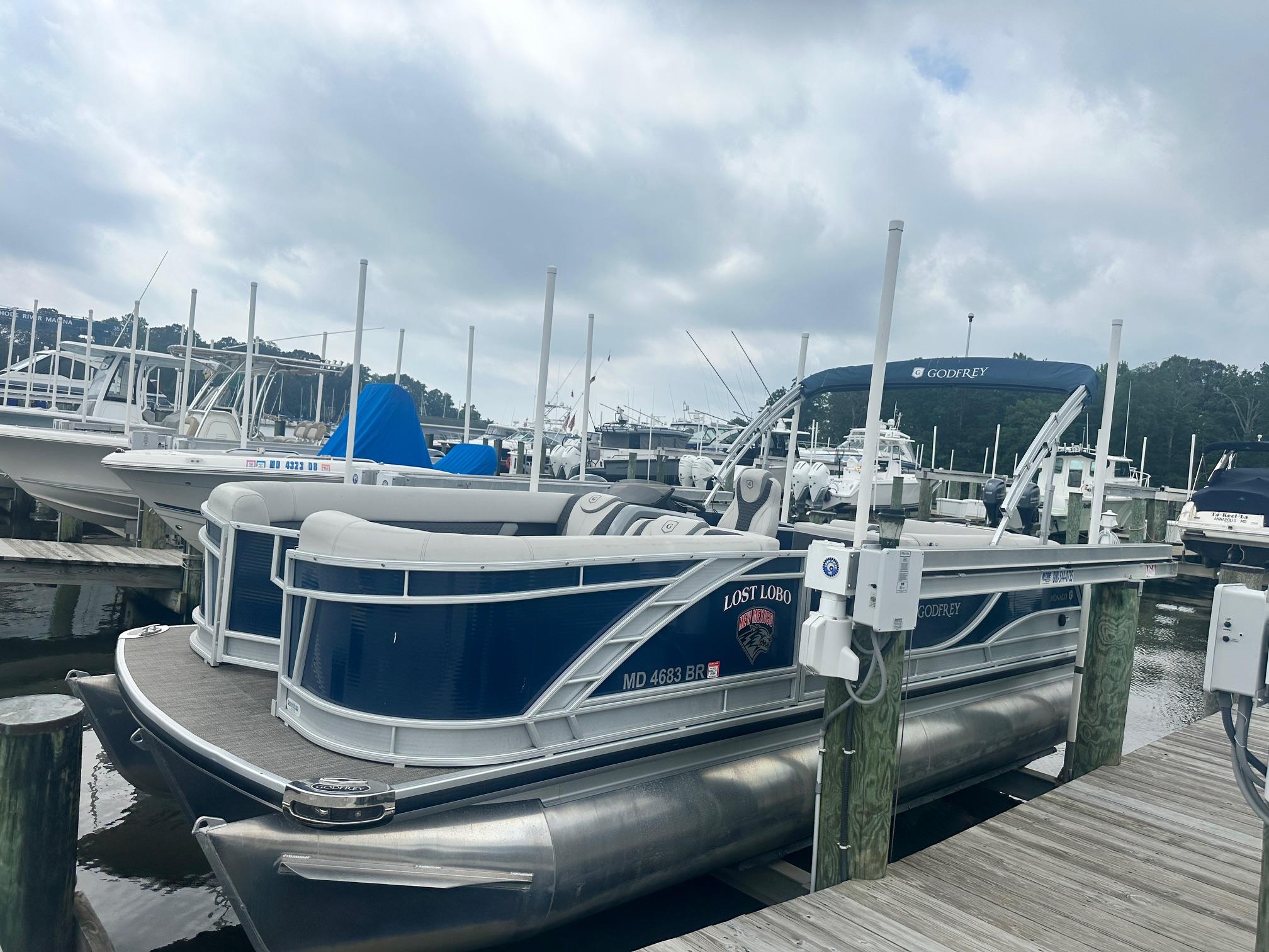 Godfrey Monaco 235 C 2021 Godfrey Monaco 235 C pontoon boat docked at marina under cloudy sky.