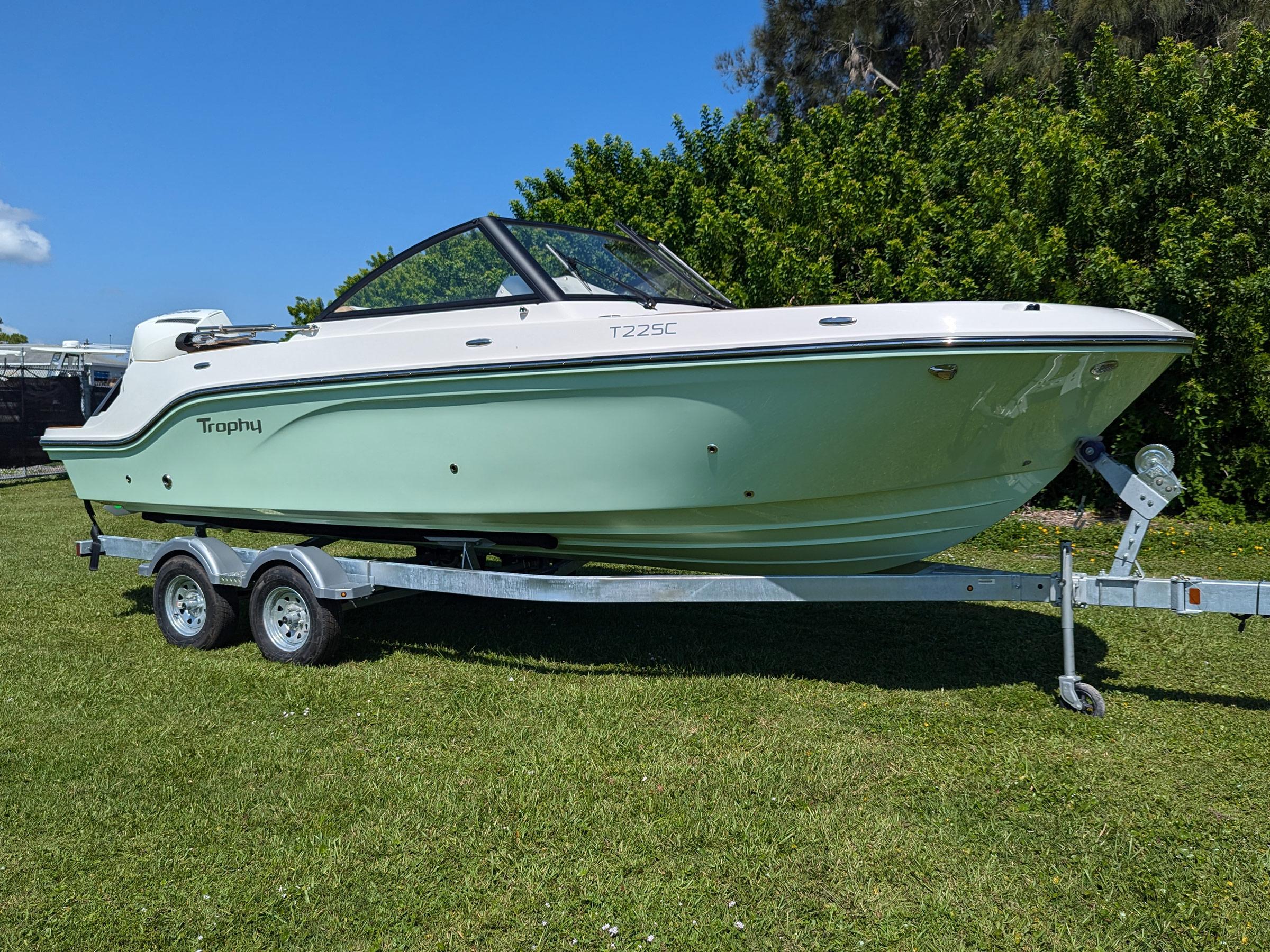 Bayliner Trophy T22SC 2026 Bayliner Trophy T22SC boat on trailer, parked on grass with trees in background.