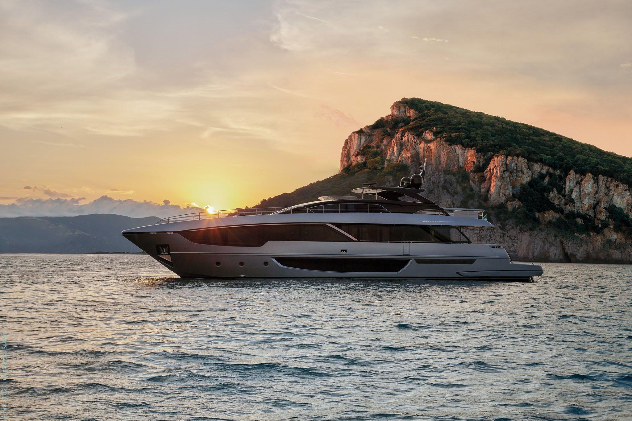 Riva CORSARO 102 2025 Riva CORSARO 102 yacht cruising at sunset near rocky coastline.