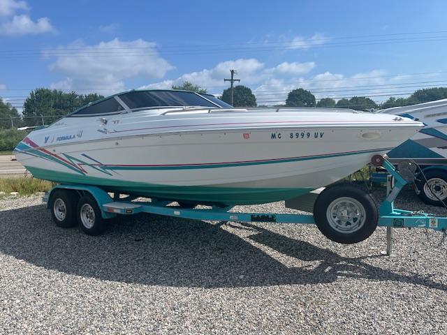 Formula 232 Ls 1996 Formula 232 LS boat on trailer, parked outdoors on gravel, under a partly cloudy sky.
