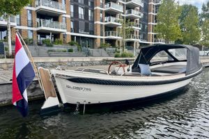 Isloep 735 | Yanmar 29pk | Nieuwe cabriokap | White Isloep 735 boat with new cabrio top, docked near modern apartments, 2007 model.