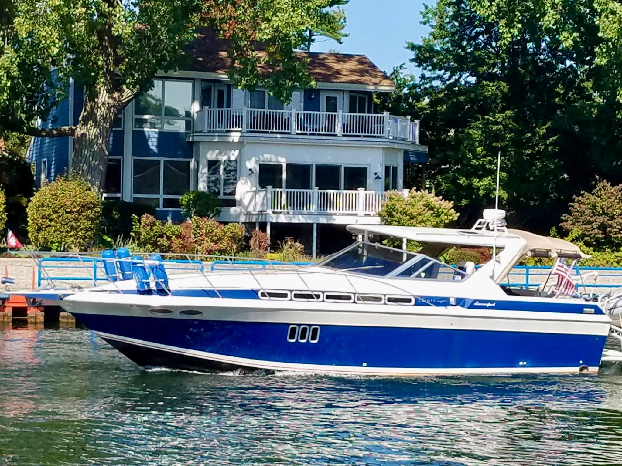 Chris-Craft 412 Amerosport 1987 Chris-Craft 412 Amerosport boat on water near a lakeside house.