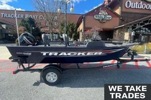 Tracker Pro Guide V-16 SC 2026 Tracker Pro Guide V-16 SC boat on trailer outside dealership, "We Take Trades" sign visible.