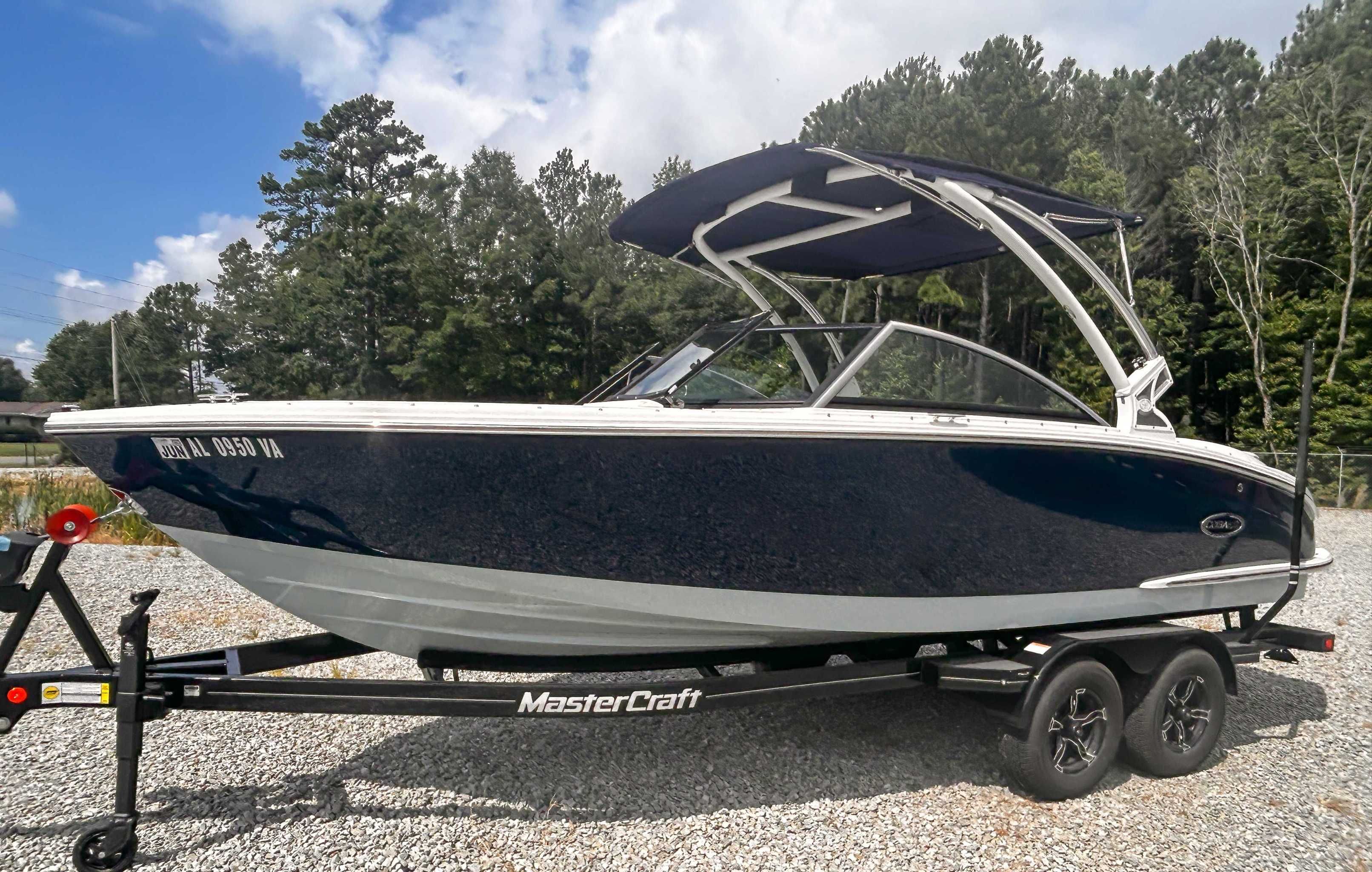 Cobalt CS23 2018 Cobalt CS23 boat on trailer, parked outdoors with trees in background.