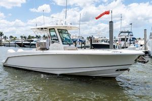 Boston Whaler 280 Outrage 2020 Boston Whaler 280 Outrage boat docked in a marina under a partly cloudy sky.