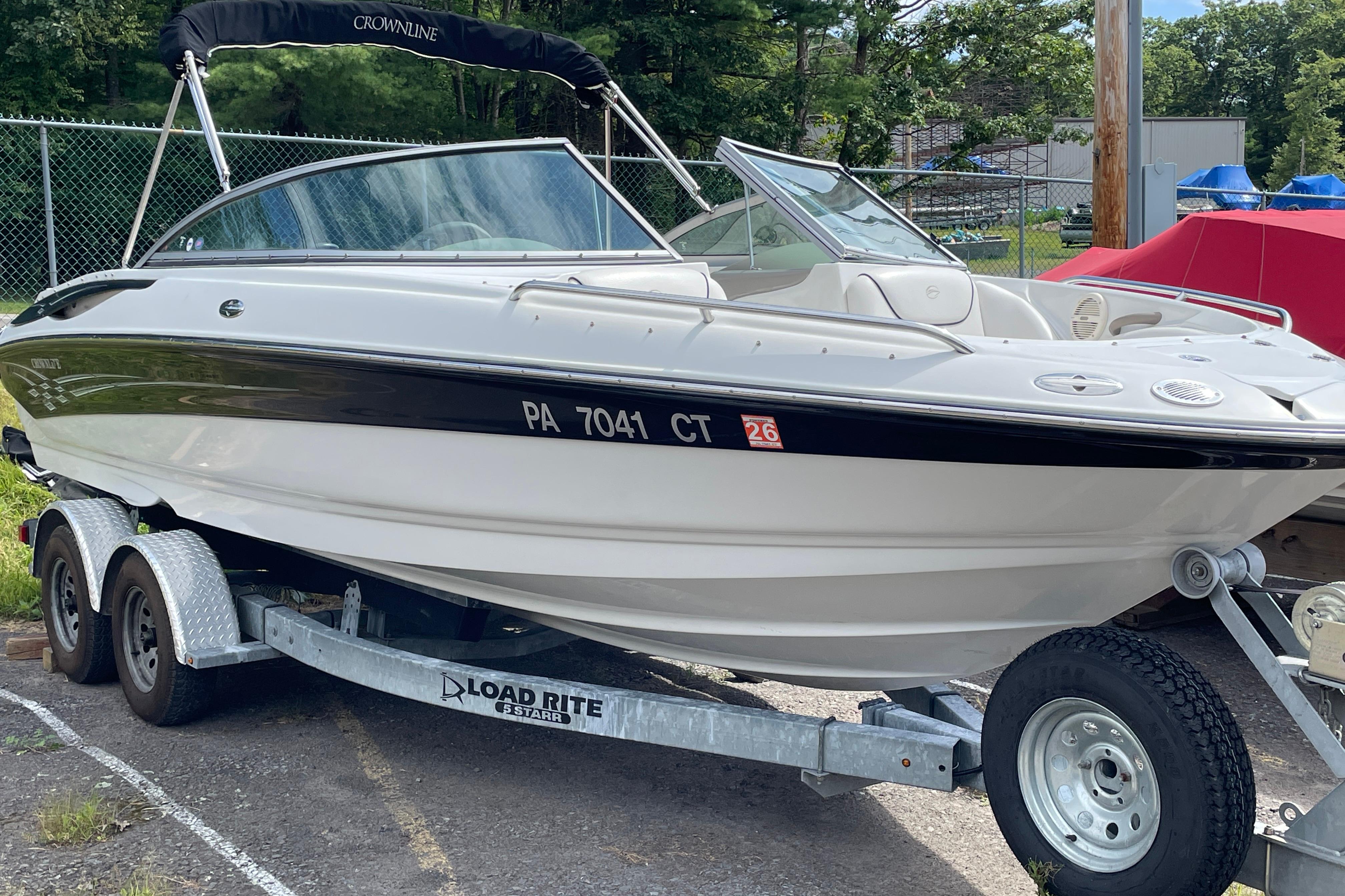 Crownline 216 LS 2004 Crownline 216 LS boat on trailer, parked outdoors with trees in background.