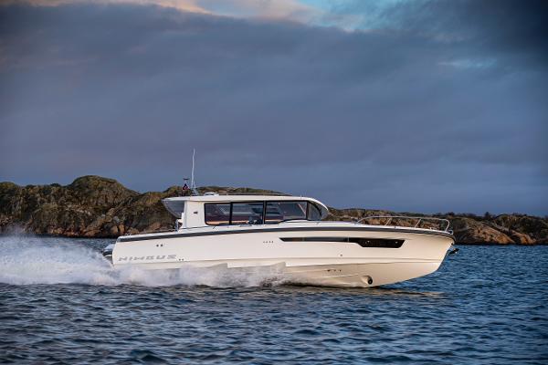Nimbus C-11 2024 Nimbus C-11 boat cruising on water near rocky shoreline.
