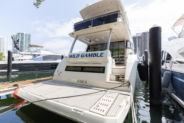 Prestige 630 Flybridge 2018 Prestige 630 Flybridge yacht docked, rear view, with "Wild Gamble" name, in a marina setting.