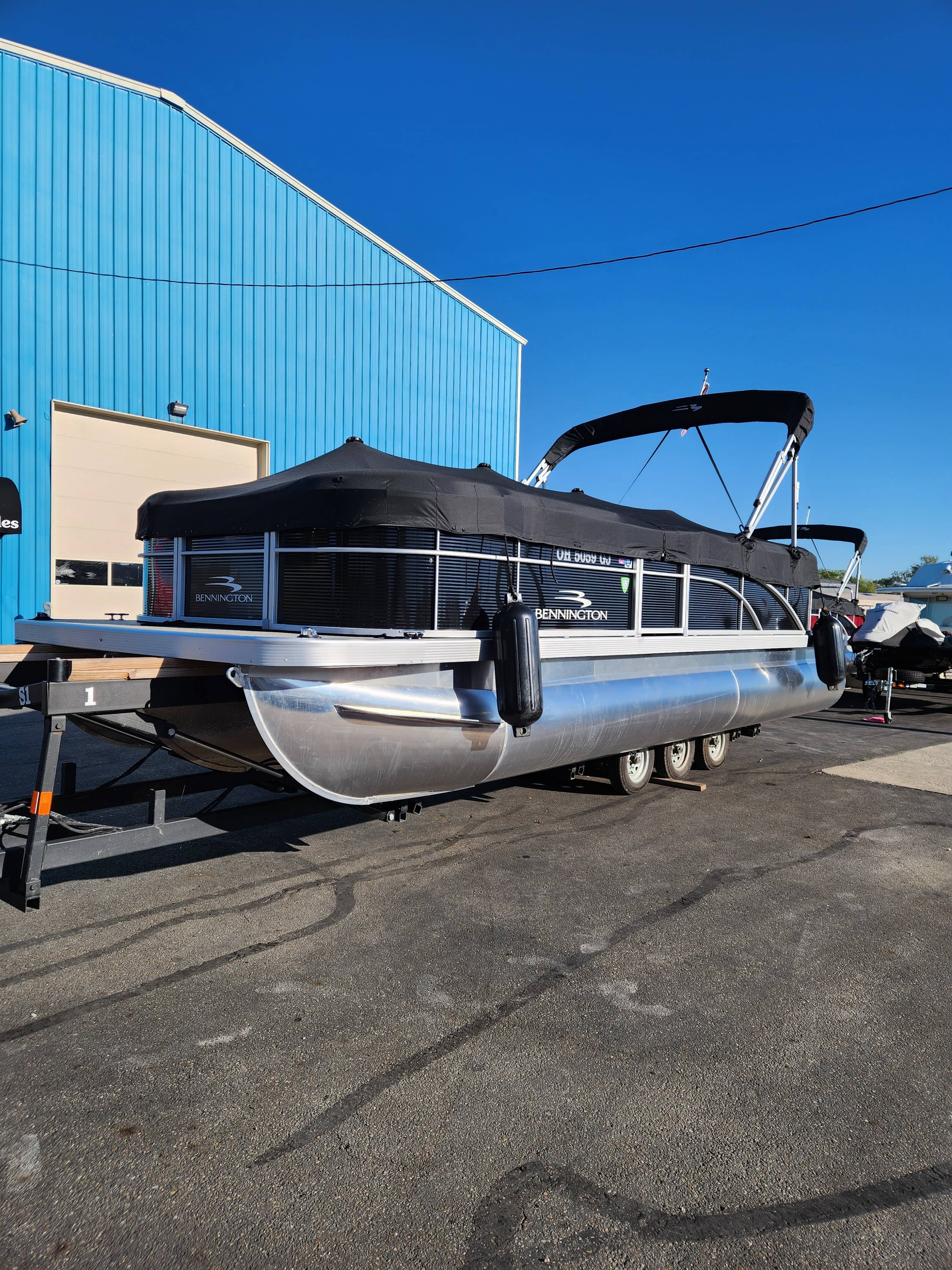 Bennington 22SVSR 2022 Bennington 22SVSR pontoon boat on trailer, parked near blue building.