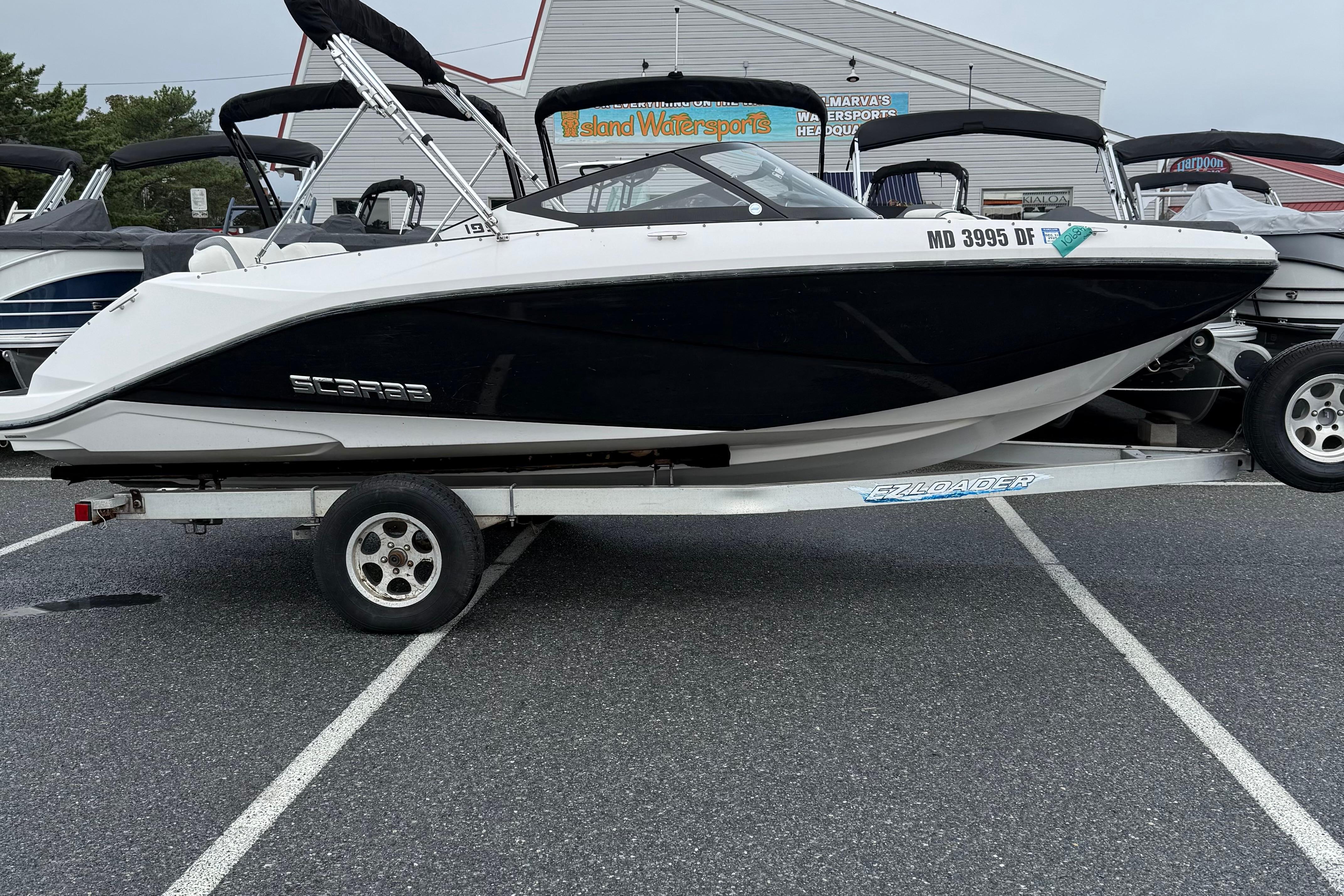 Scarab 195G 2019 Scarab 195G boat on trailer in parking lot, side view.