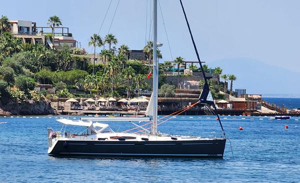 Beneteau Oceanis 54 2009 Beneteau Oceanis 54 sailboat anchored near a scenic coastal resort.