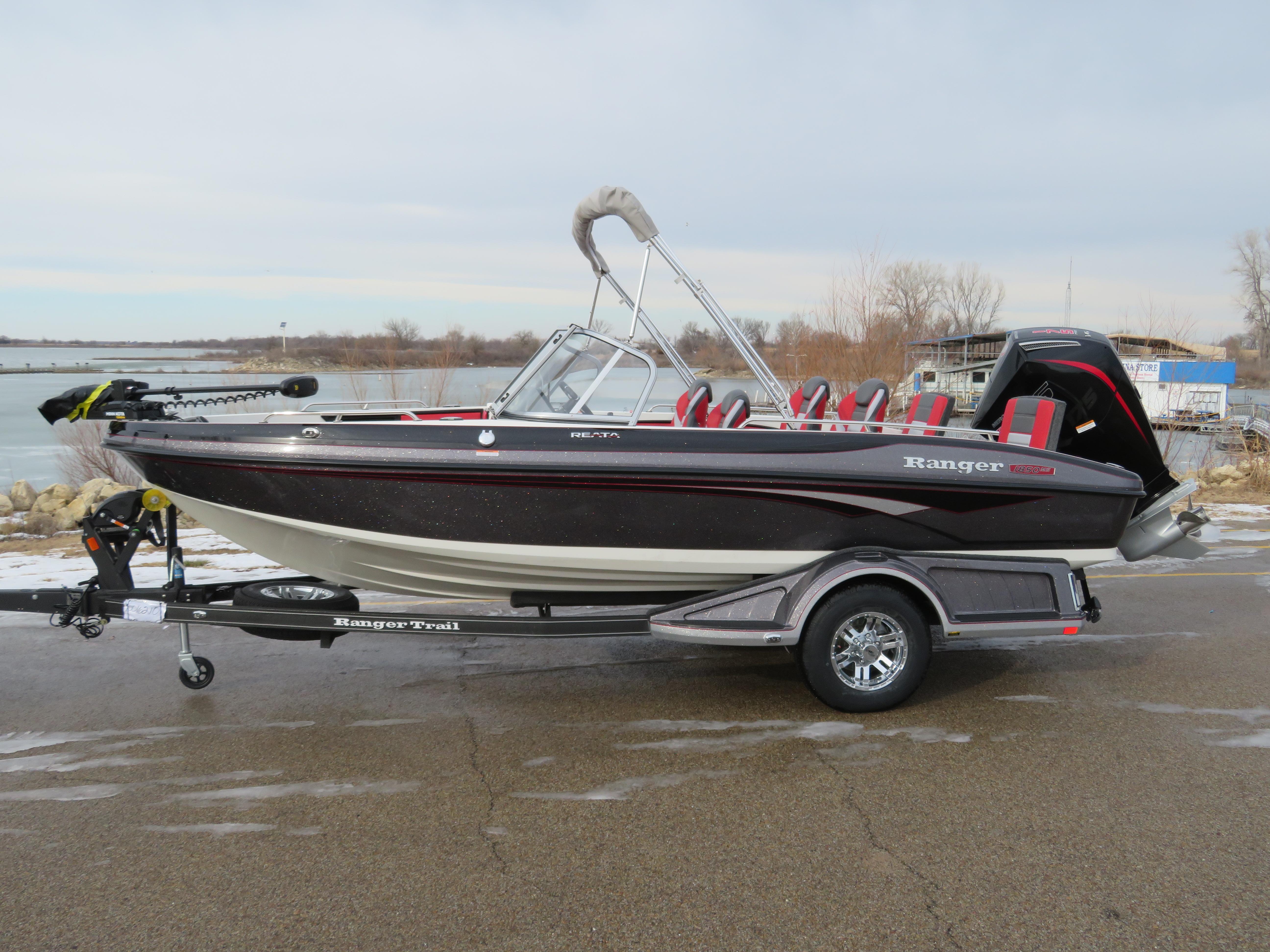 Ranger 1850MS 2025 Ranger 1850MS boat on trailer by a lake, featuring sleek design and red seating.