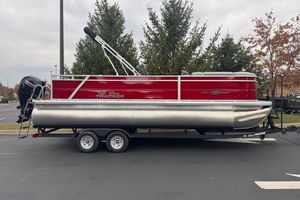 Sun Tracker Party Barge 22 RF DLX 2026 Sun Tracker Party Barge 22 RF DLX pontoon boat, red and silver, parked outdoors.