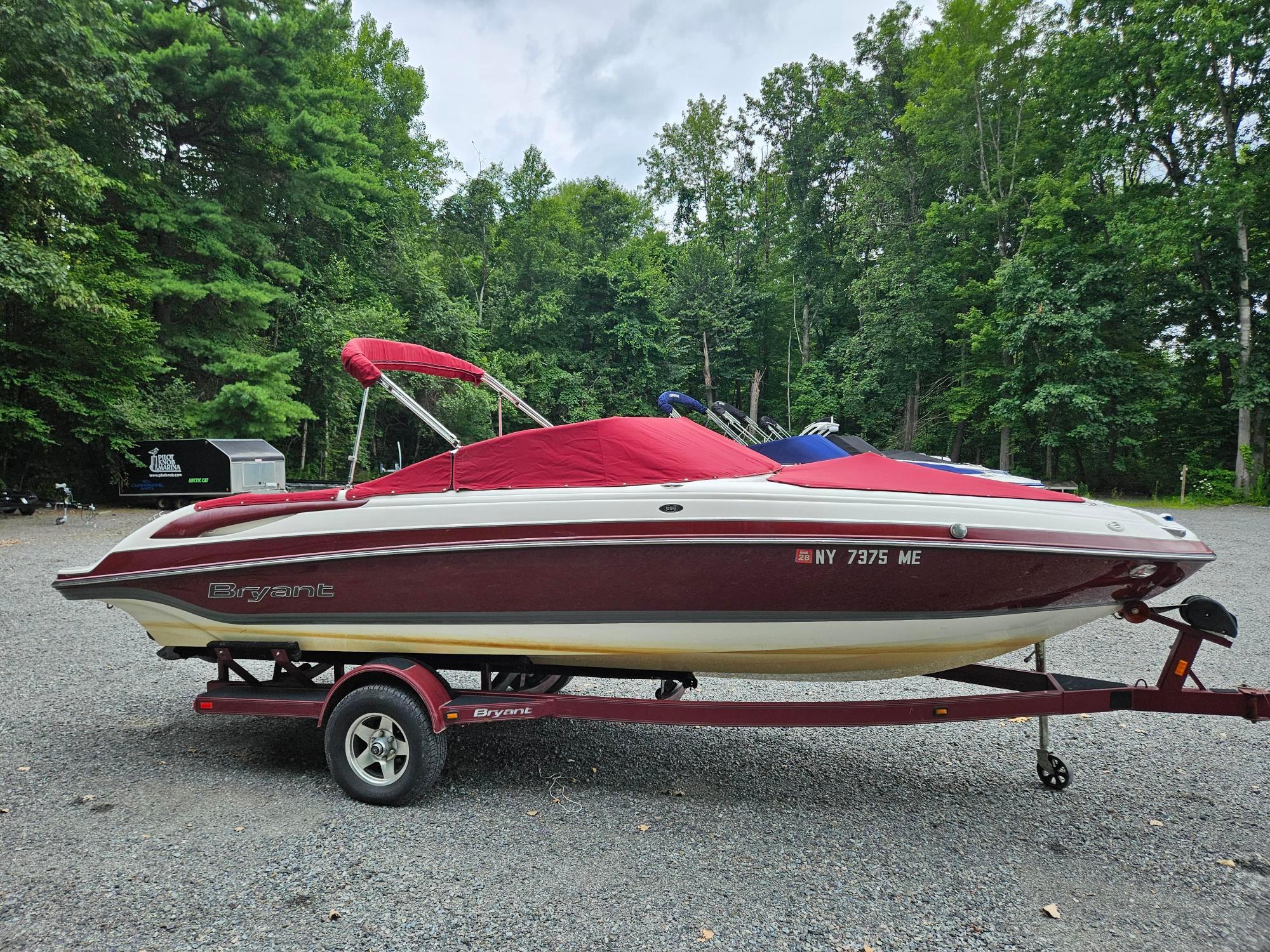 Bryant 233 Red and white 2008 Bryant 233 boat on trailer, parked in wooded area.