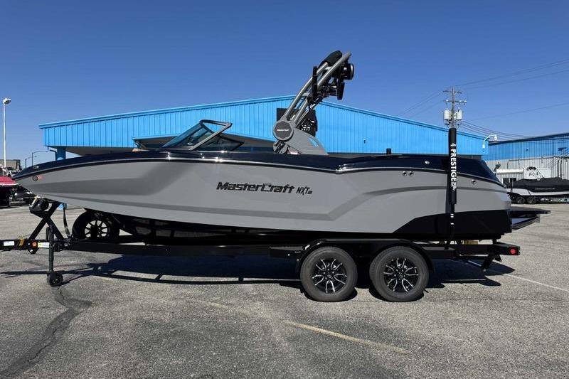 MasterCraft NXT22 2026 MasterCraft NXT22 boat on trailer, parked outdoors near blue building.