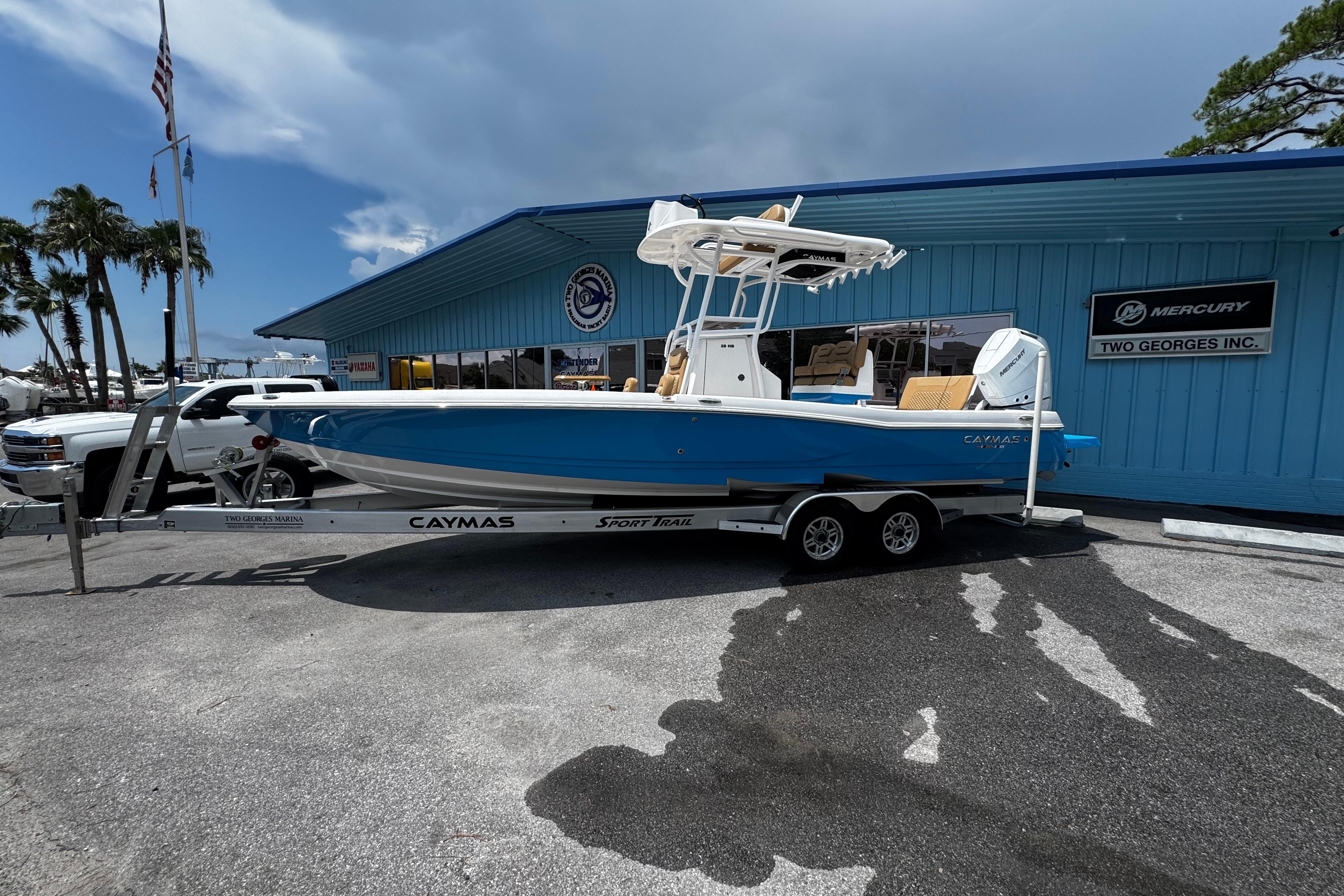 Caymas 28 HB 2026 Caymas 28 HB boat on trailer outside dealership, blue hull, sunny day.