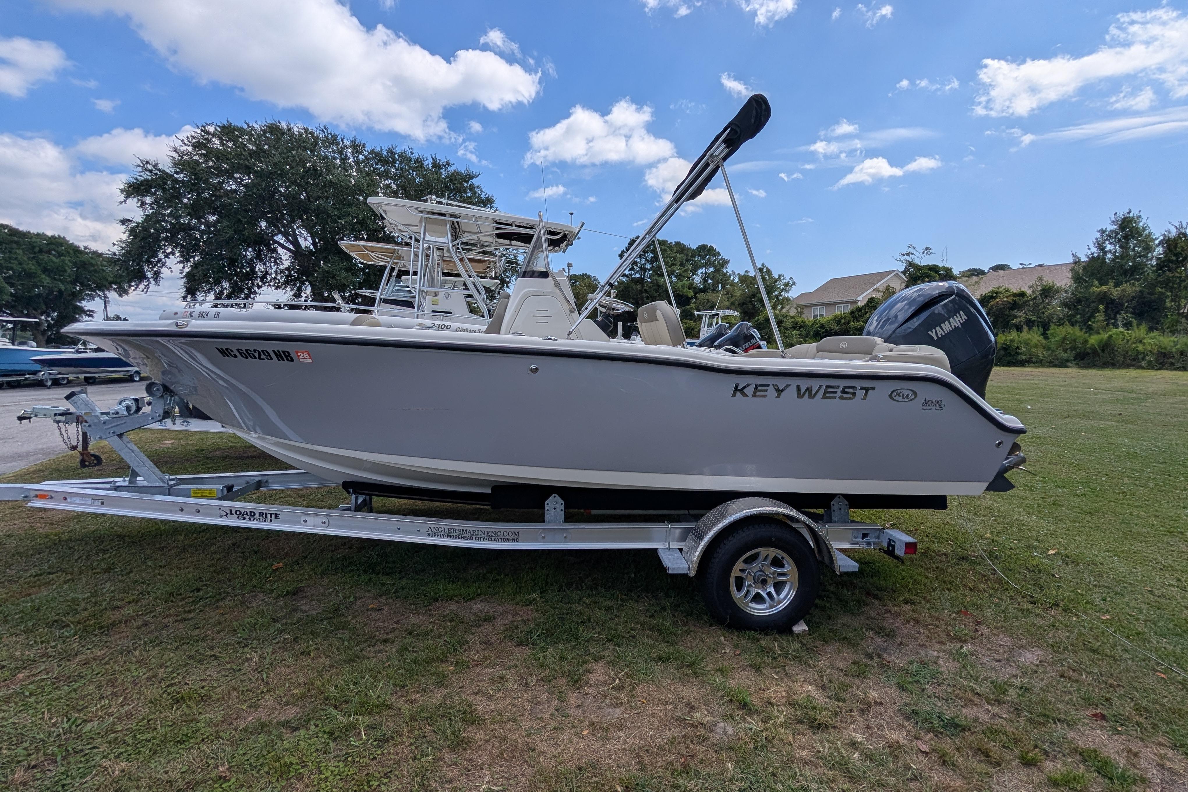 Key West 203 FS 2023 Key West 203 FS boat on trailer, parked on grass under blue sky.