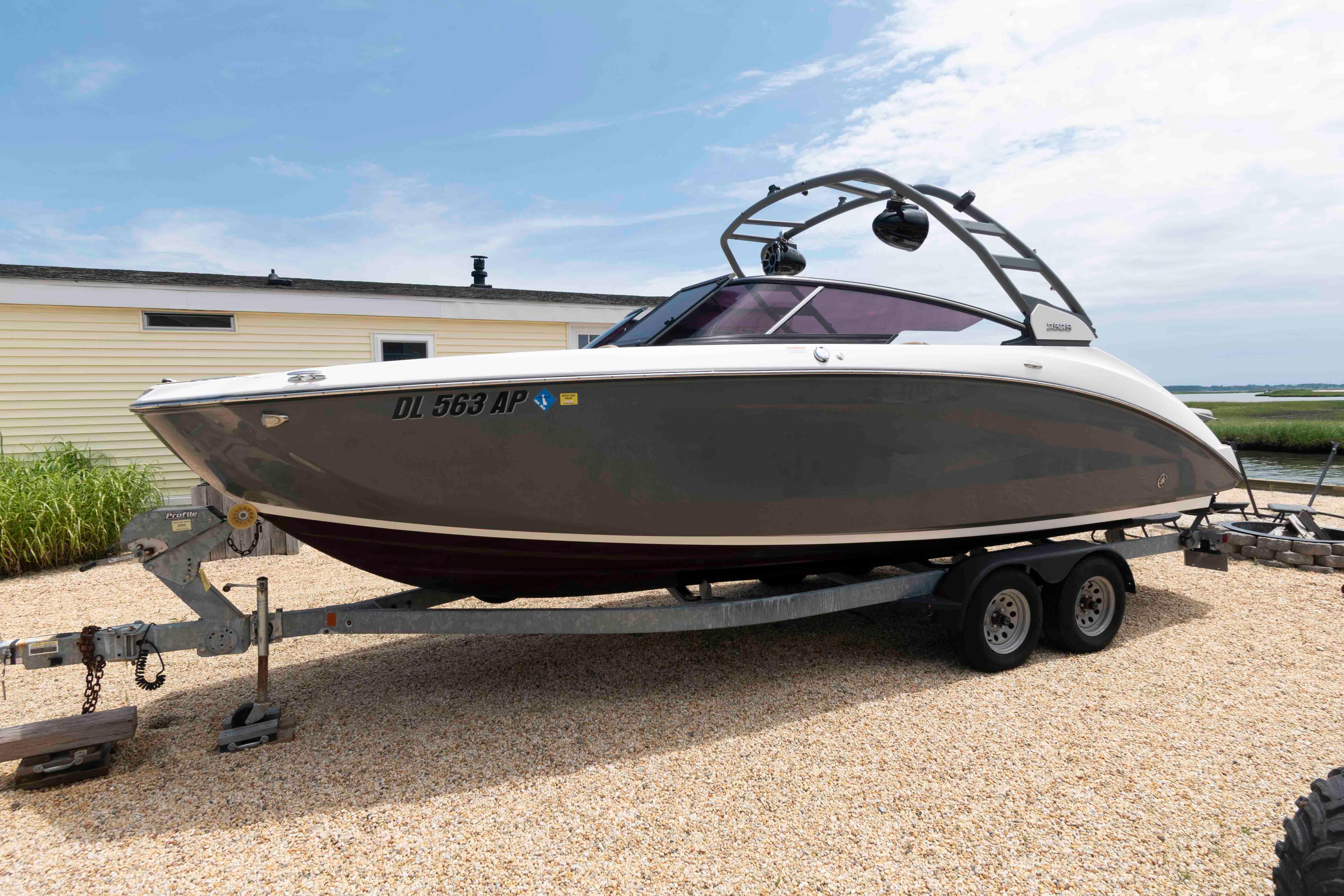 Yamaha Boats 252S 2021 Yamaha Boats 252S on trailer, parked outdoors near a house, under a clear sky.