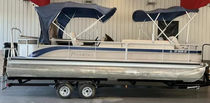 Premier RE 250 2T 2006 Premier RE 250 2T pontoon boat with blue canopy on trailer in garage.