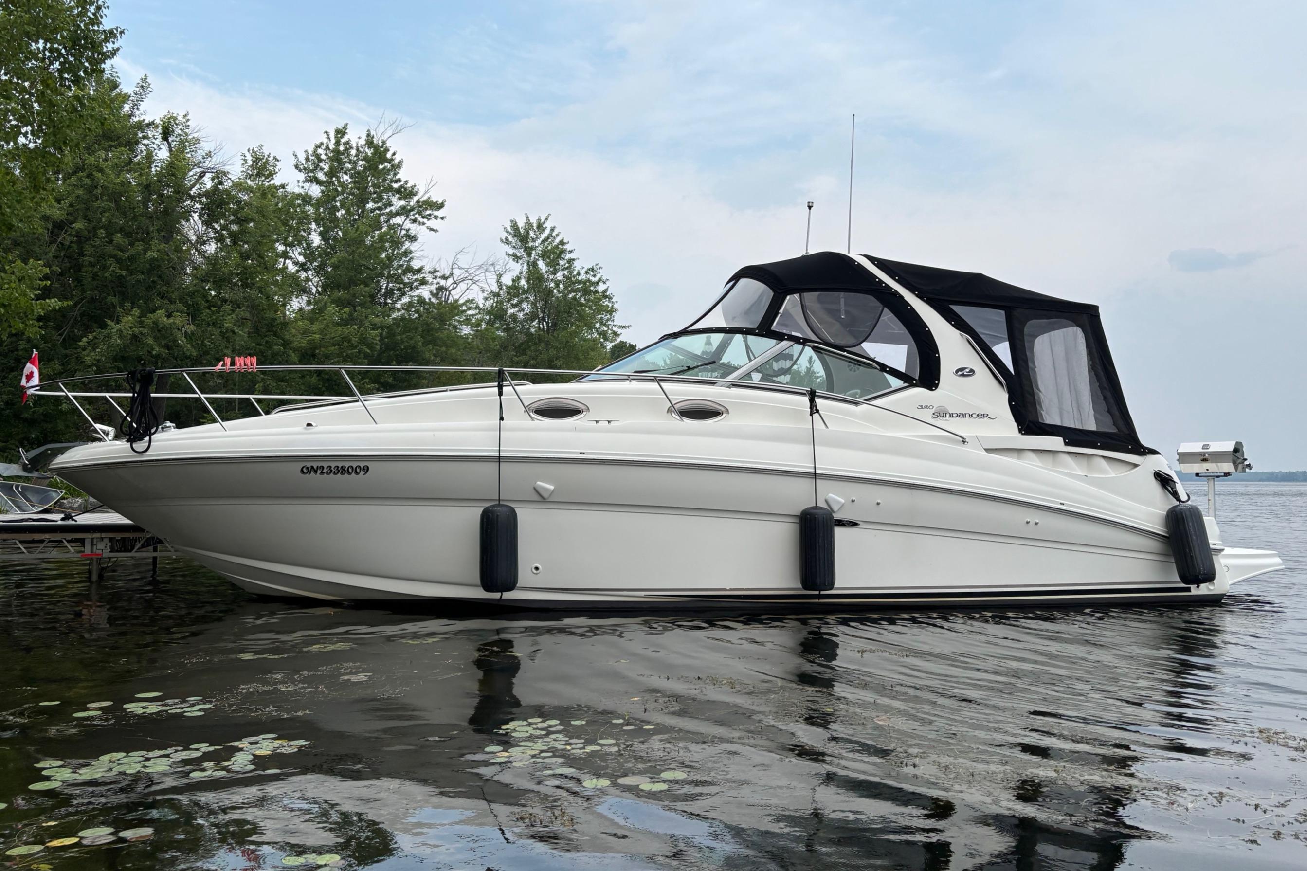 Sea Ray 320 Sundancer 2004 Sea Ray 320 Sundancer boat docked on a calm lake with trees in the background.