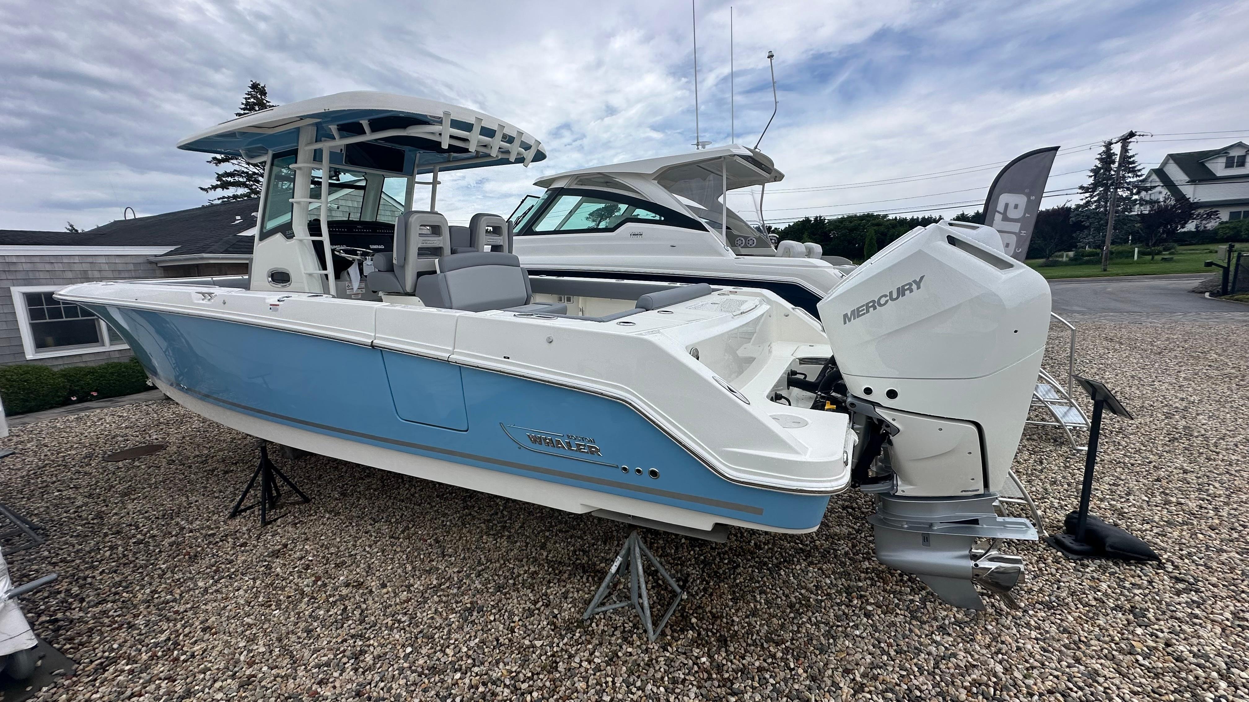 Boston Whaler 330 Outrage 2025 Boston Whaler 330 Outrage boat with Mercury engine, displayed outdoors on gravel.